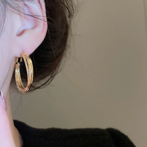Close-up of gold multi-layered hoop earrings on a model showing minimalist vintage style