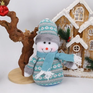 Detail eines blau-weißen gestrickten Weihnachtsschneemanns mit festlicher Winterdekoration