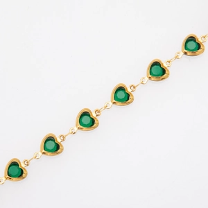 Macro shot of gold-plated heart-shaped links with green gemstones on a bracelet
