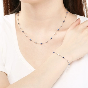 Detail view of a beaded four-leaf clover necklace and bracelet set on a model