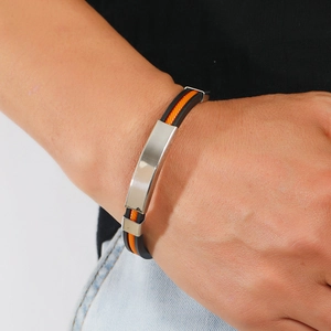 Détail d'un bracelet pour homme en silicone orange et noir avec plaque en acier poli