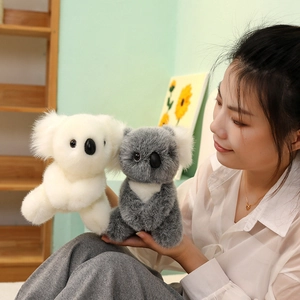 Plush koala toy set in grey and white colors, held by a model in a cozy home setting