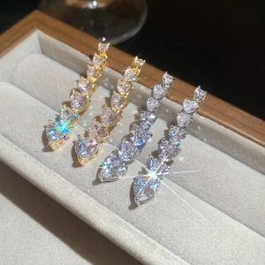 Detail view of gold and silver heart gradient zircon earrings on a velvet display tray