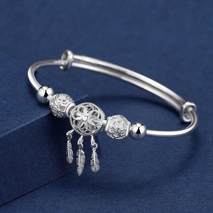 Macro detail of 999 silver dreamcatcher bracelet with heart pendant and feather charms