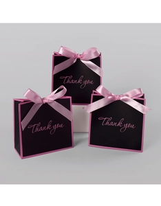 Detailed view of black paper gift bags with pink ribbon bows and Thank You text