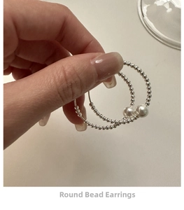 Detail of silver beaded earrings with elegant pearls held in hand for size display