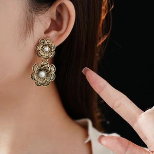Close-up of vintage gold flower earrings with white pearls worn by a fashion model