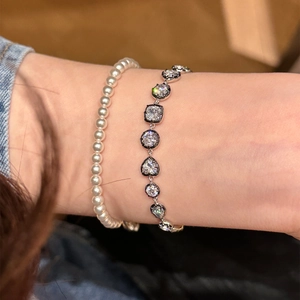 Close-up of stacked sparkling zircon silver chain and white pearl bracelet on wrist