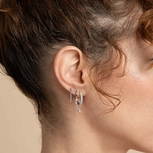 S925 sterling silver star drop earrings and cubic zirconia hoops on model's ear