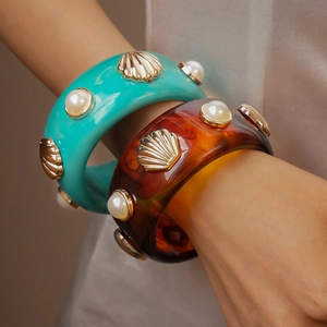 Detail of wide resin bangles with turquoise and amber textures plus faux pearls