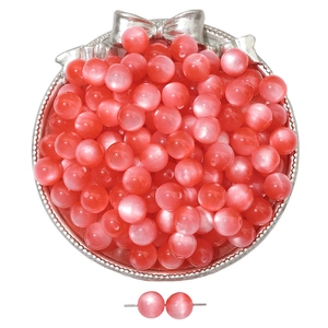 Detalle macro de cuentas de vidrio rosa ojo de gato para joyería DIY en bandeja plata