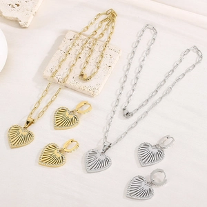 Flat lay of gold and silver heart jewelry sets with necklaces and earrings on stone