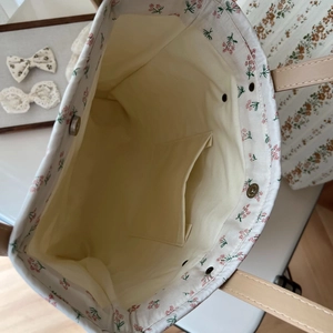Détail d'un sac cabas fleuri avec fermeture magnétique, poche intérieure et anses en cuir