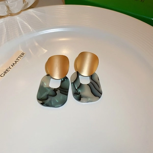 Detail of gold plated hoop earrings with dark green leopard print texture on white plate
