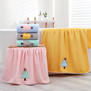 Detail of coral fleece towels featuring Christmas tree embroidery and plush pom-poms decoration