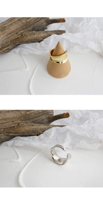 Detailed view of polished gold and silver minimalist wide-band open rings on white decor