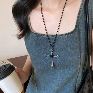 Detail shot of vintage silver cross pendant with black bead necklace and center stone