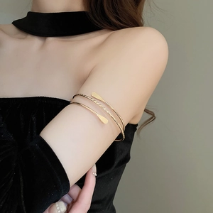 Detail of a multi-layer gold arm cuff with twisted rope texture and smooth metal finish