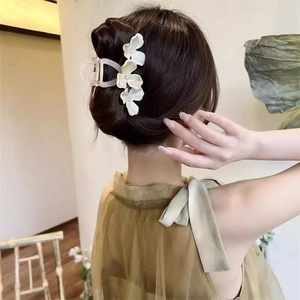 Detail van crème witte drievoudige bloem haarklem met parels op een elegante knot kapsel