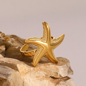 Vue macro d'une bague étoile de mer dorée avec texture martelée sur fond pierre