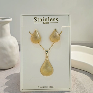 Detail view of gold stainless steel jewelry set with teardrop earrings and pendant necklace