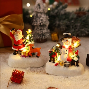 Close-up of resin Christmas house with Santa and reindeer glowing on faux snow