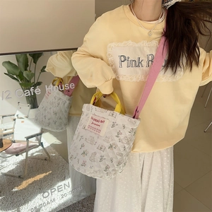 Détail du sac seau matelassé à fleurs avec étiquette coeur et poignées jaunes