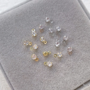 Sparkling gold and silver zircon pendant charms scattered on a grey velvet jewelry tray
