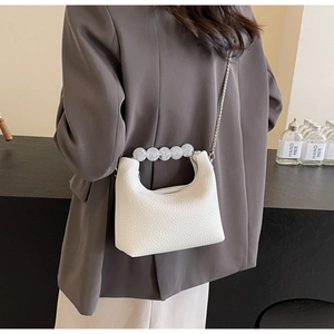 Detail of white lychee leather bag with pearl handle and silver chain on model