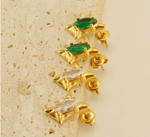 Macro view of 18k gold earrings with emerald and clear marquise zirconia gems