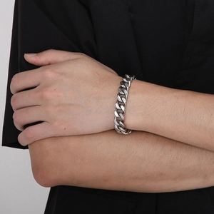 Close-up of polished silver stainless steel Cuban chain bracelet on male model wrist
