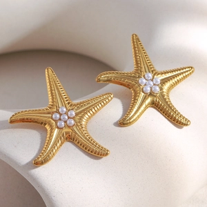Close-up of gold plated starfish earrings with textured surface and white pearl center