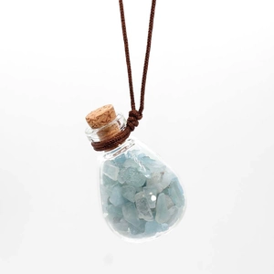 Detail of a glass pendant filled with light blue crushed crystals and a cork stopper