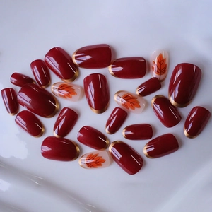 Faux ongles bordeaux avec pointes dorées et motifs de feuilles d'érable d'automne
