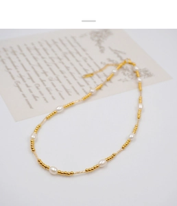 Detail of elegant freshwater pearl necklace with golden beads and stainless steel tubes