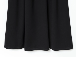 Detail shot of black woven fabric showing high-quality pleated hem and elegant drape texture