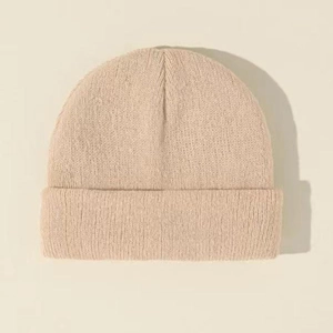 Detailed close-up showing the soft beige knit texture and ribbed cuff of the beanie hat
