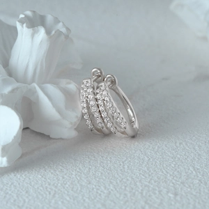 Macro shot of elegant S925 silver huggie earrings with triple-row pavé diamond setting