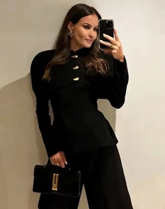 Detailed view of women's black long-sleeve top with decorative gold fish-shaped metal buttons