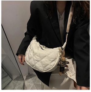Detail of white quilted crescent bag with diamond stitching and cute rabbit charm