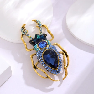 Detail of golden beetle brooch featuring blue rhinestones and black onyx stones
