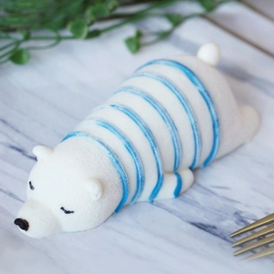 Detail of sleeping polar bear mousse cake on marble surface with gold fork accessory