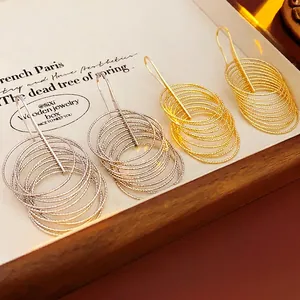 Layered gold and silver multi-circle drop earrings with spiral texture on a display tray
