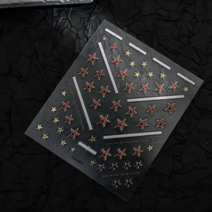 Macro shot of 3D gold and red star nail stickers with Co-551 model label on dark background