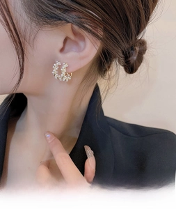 Macro side view of a model wearing twisted golden hoop earrings with micro pearls