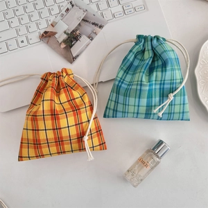 Close-up of tartan plaid drawstring pouches in warm orange and cool green cotton canvas