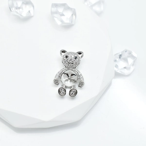 Silver bear pearl pendant setting with shimmering stones on a white geometric display