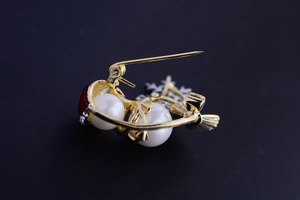 Detailed view of a gold cherry brooch with pearls and red accents for Christmas