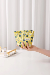Close-up of jacquard floral makeup bag featuring a golden flower zipper pull and brand tag