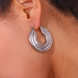 Detailed close-up of a large silver hollow hoop earring with vertical striped texture